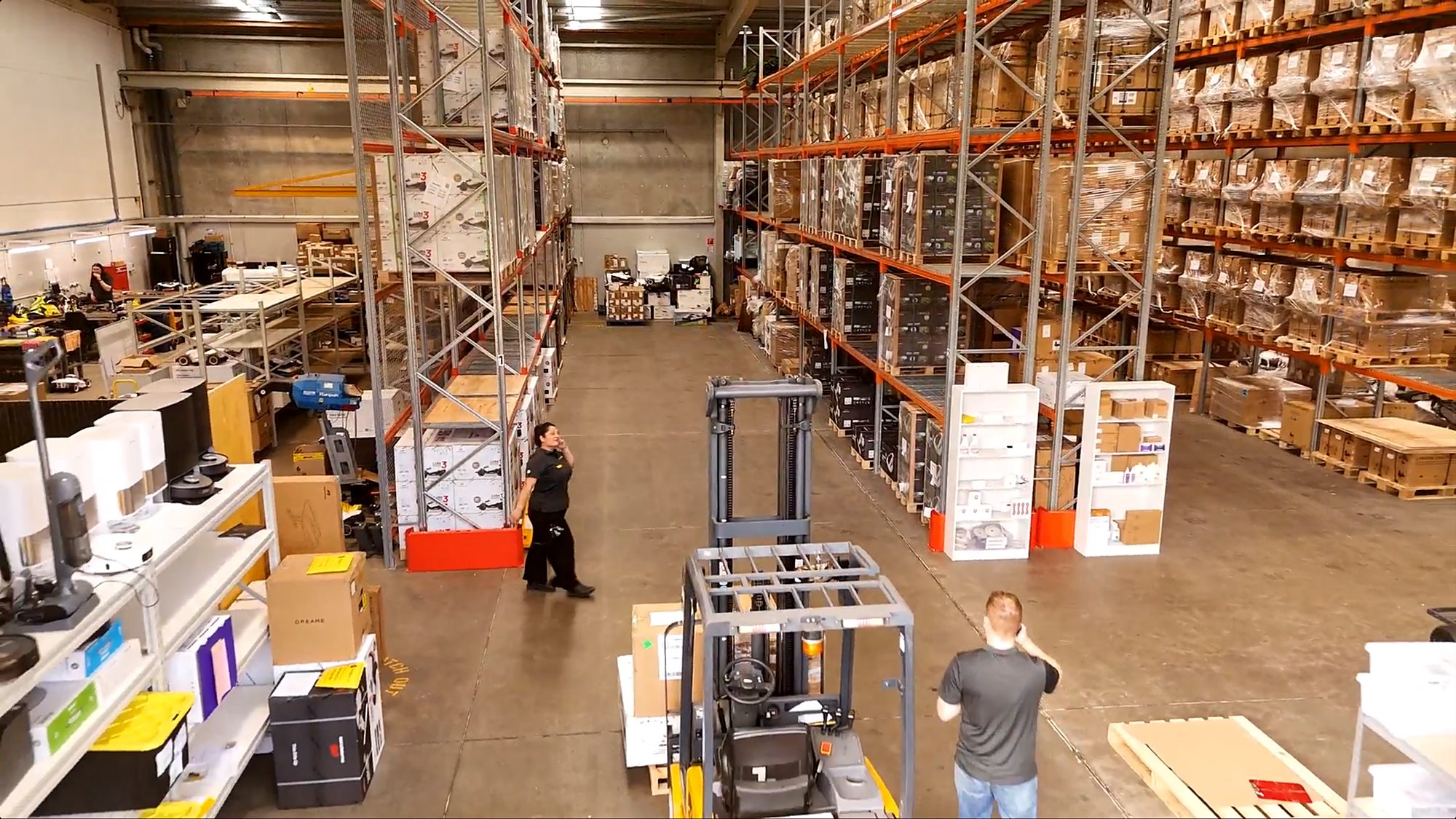 A Silk Lane Group distribution centre, with pallet racking to the ceiling on both sides of the aisle, a forklift in use and staff picking orders